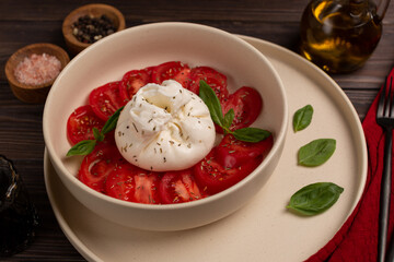 Salad of fresh tomato and cream cheese burrata, with dried herbs, olive oil and basil