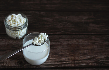 homemade cottage cheese with kefir in a glass glass with a spoon on a wooden background