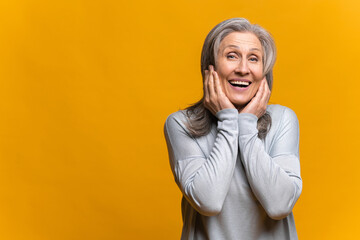 Smiling positive female with attractive look, posing against yellow blank wall. Happy woman showing...