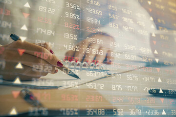 Double exposure of woman's hands making notes with forex graph hologram. Concept technical analysis.
