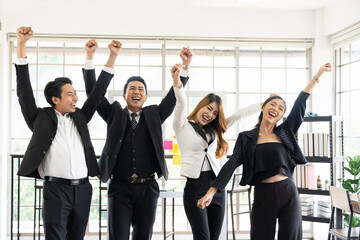 Fototapeta premium Portrait of business Asian people raising their arms during meeting in the office. Group of diverse businesspeople celebrate shared business strategy plan success.