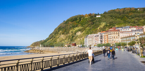 Panorama of people walking the promenade at the Zurriola beach in San Sebastian, Spain