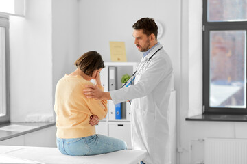 medicine, healthcare and people concept - male doctor with clipboard comforting sad woman patient...