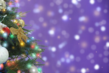 Beautiful Christmas tree with bright baubles against blurred lights on violet background, closeup. Space for text