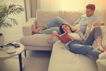 Happy couple with book on sofa in living room