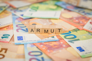 Das Wort Armut – in deutsch für poor -  auf Geldscheine Euro Euroscheine mit Holzwürfel...