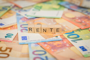 Das Wort Rente – in deutsch für annuity -  auf Geldscheine Euro Euroscheine mit Holzwürfel geschriebener Text