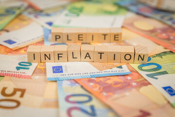 Das Wort Inflation und Pleite – in deutsch für Bankruptcy -  im Hintergrund auf Geldscheine Euro...