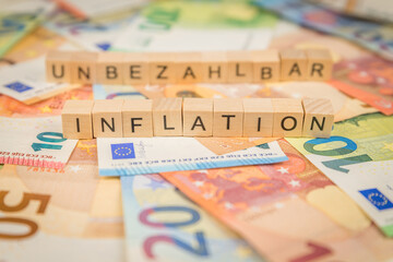 Das Wort Inflation und Unbezahlbar – in deutsch für Priceless -  im Hintergrund auf Geldscheine...