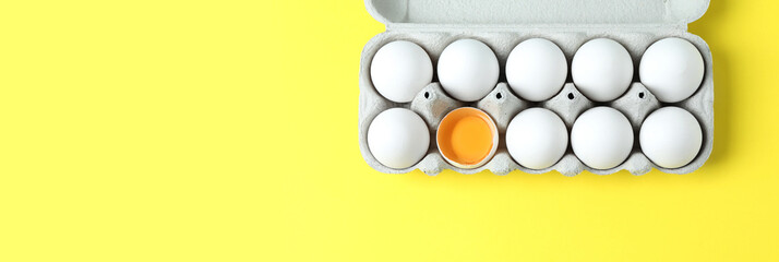 Carton of fresh raw chicken eggs on yellow background, top view with space for text. Banner design