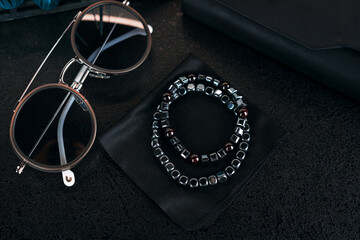 Handmade bracelets made of natural stones on a black cloth. Silver jewelry, sunglasses, close-up