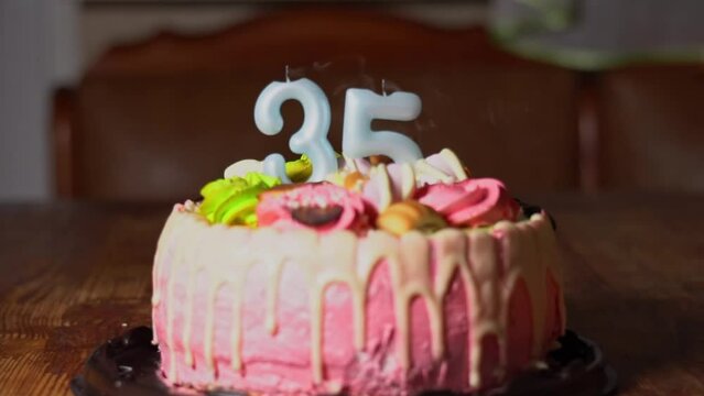 Blowing out candles on a birthday cake. 35th birthday. Birthday cake with a burning birthday candle. Happy Birthday background anniversary celebration concept. High quality FullHD footage