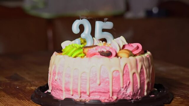 Blowing out candles on a birthday cake. 35th birthday. Birthday cake with a burning birthday candle. Happy Birthday background anniversary celebration concept. High quality FullHD footage
