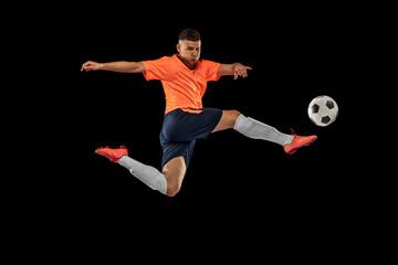 Fototapeta na wymiar Dynamic portrait of professional male football soccer player in motion isolated on dark background. Concept of sport, goals, competition, hobby, achievements