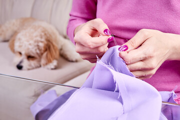 Close-up of the girl rips the seam on the dress using a seam ripper against the background of a...