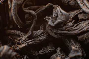 Black loose leaf tea as a background. Texture of dry black tea leaves. Dark background. Extreme macro mode. black leaf tea closeup