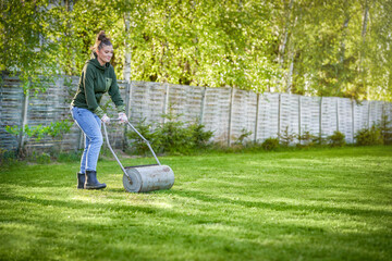 Woman working with lawn roller in the garden