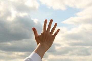 Young man right hand and sky with clouds. Photo was taken 19 May 2022 year, MSK time in Russia.