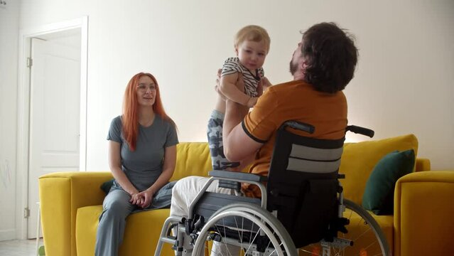 Man in a wheelchair playing with his baby and his wife