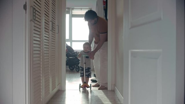 A father rolls his little son on a small scooter in