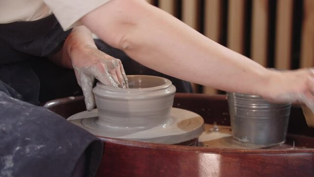 Hands of elderly woman widing a hole in piece of wet