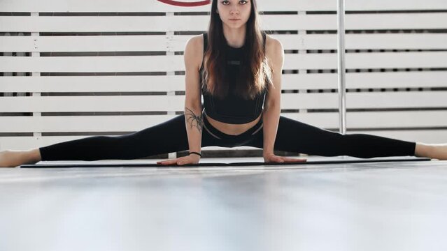 Fitness - a young woman gymnast sits in a splits and
