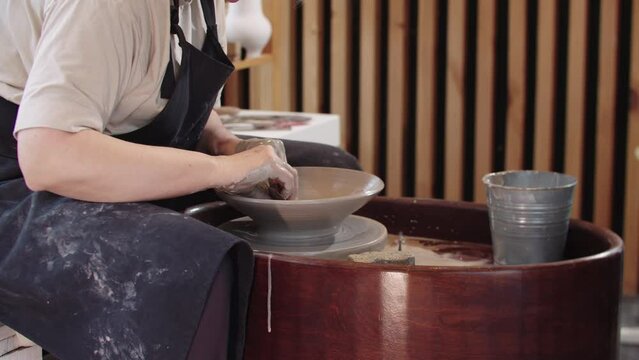 An elderly woman shaping a soup plate out of piece