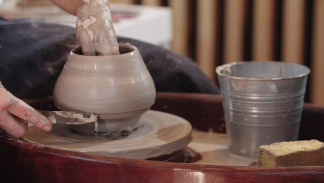 An elderly woman shaping a clay pot on moving pottery