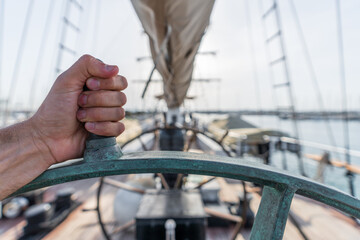 Left hand squeezing ship wheel with blurred background © F.C.G.