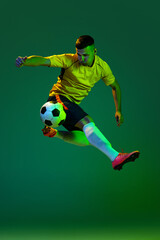 Studio shot of young professional male football soccer player in motion isolated on green...