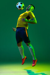Studio shot of young professional male football soccer player in motion isolated on green...