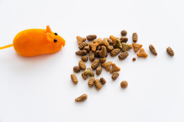 top view of dry cat food near orange rubber mouse isolated on white.