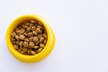 top view of yellow plastic bowl with pet food isolated on white.