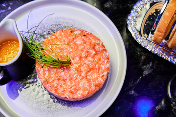 Salmon tartare with avocado on a white plate in a restaurant. Close-up, selective focus
