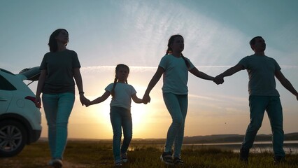 Naklejka premium people in the park. happy family a silhouette walk at sunset. car travel kid dream concept. happy family parents and fun children walk silhouette next to car. family walk next sunset to car