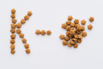 top view of dry pet food near letter k isolated on white.