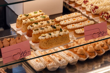 Eclairs on the shelf of a pastry shop or cafe. Tasty french sweets on window shop, delicious pastries for coffee. Cakes in pastry shop, variety of desserts with creamy topping on display in bakery