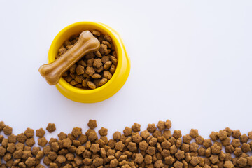 top view of yellow plastic bowl with pet food and dog treat isolated on white.