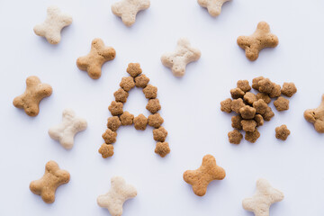 top view of bone shaped pet treats near letter and dry pet food isolated on white.