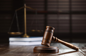 Wooden gavel, scales of justice and books on table against blurred background