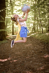 Little girl wearing in super hero clothing holding globe at the forest