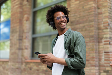 Fototapeta premium Handsome young man with headphones. Man listening the music while walking through the city.