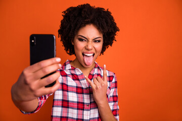 Photo of excited lady use gadget make selfie show horned symbol protrude tongue isolated shine...