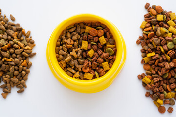 top view of different dry food for pets and yellow bowl isolated on white.