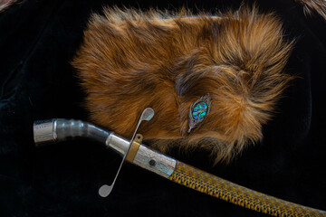 An ancient saber. A chic version of a combat weapon lying on a fur cape next to a hat. The...