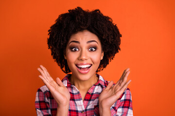Photo of excited funky lady dressed checkered shirt rising arms smiling isolated orange color...