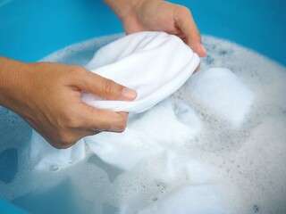 Woman hands washing white clothes in sink. closeup photo, blurred.