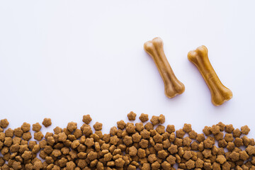 top view of bone shaped pet treats near pet food on white.