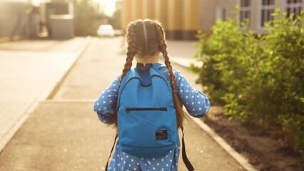 school. girl kid runs with a backpack to school. student concept. cheerful girl with a backpack...