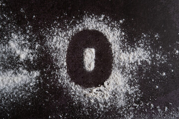 The number 0 is written on scattered white flour through a stencil.